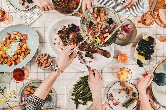 Overhead view of a dinner table with plates of food being passed.