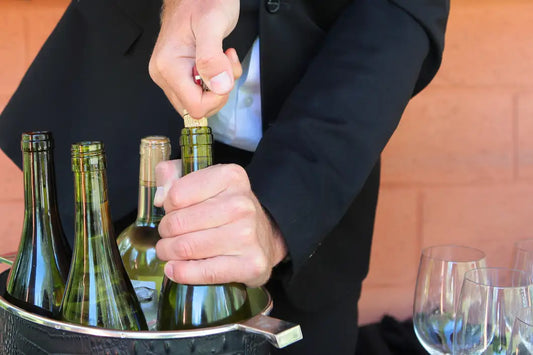 A man's hands opening a bottle of wine.