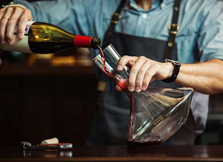 Hands decanting a bottle of red wine