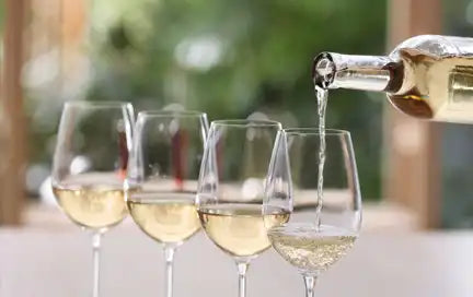 Four glasses of white wine being poured.