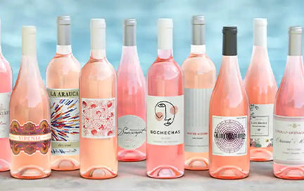 Several bottles of rosé wine in front of a body of water.