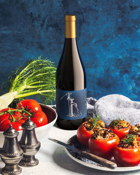 Bodewell 2020 Pinot Noir Santa Lucia Highlands, California on a table with tomatoes and stuffed peppers