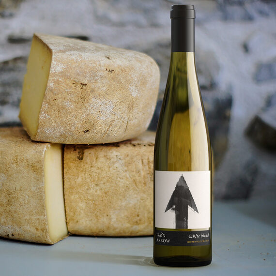 Iron Arrow 2019 White Blend Columbia Valley, Washington next to three cheese wheels