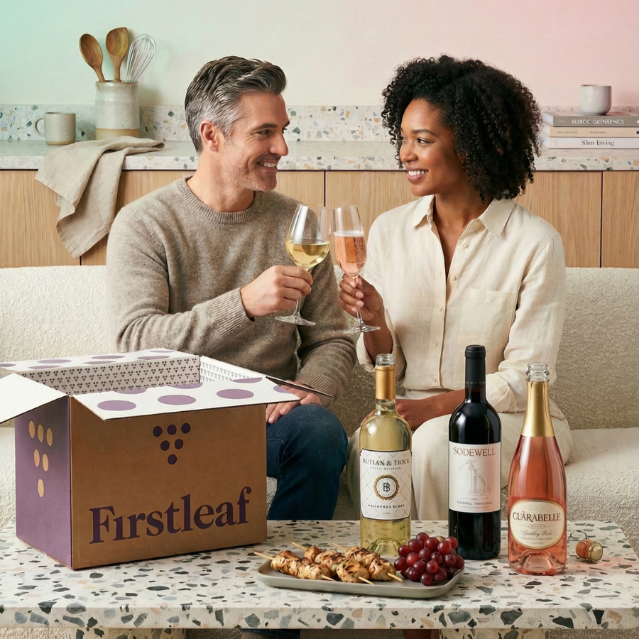 Graphic, an open Firstleaf box, six bottles of wine, and a fruit and cheese platter sitting on a kitchen counter.