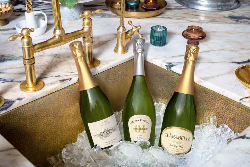 Three bottles of sparkling wine in a sink full of ice.