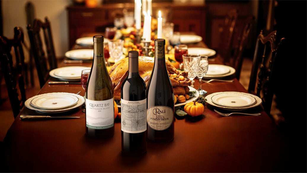 Wine bottles on a festive dining table with candles and food.