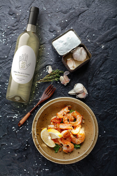 Viña Salas y Gómez 2020 Sauvignon Blanc Valle Central, Chile on a table with garlic and shrimp