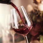 Red wine being poured into a glass with a blurred background