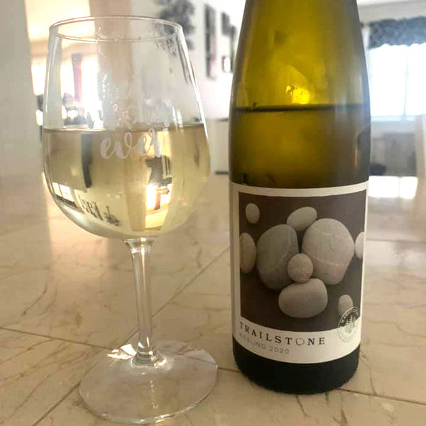 Wine bottle and glass of white wine on a kitchen counter
